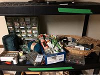 Wide view of sewing supplies including thread spools, tape measures, yarn, and more spread on a shelf