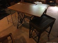Singer treadle metal base table with handcrafted wood top, wicker side table, and vintage wire telephone table shown in room corner.