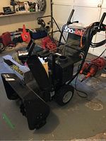 Front and side view of the snow blower showing auger housing, chute, controls and wheels