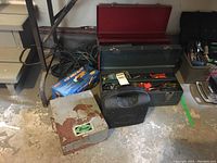 Photo showing large red tool box, smaller grey tool box, Dwyer oil burner testing kit case, black multi-tool case, extension cord, and boxed angle grinder.