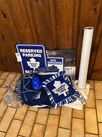 Photo of assorted Toronto Maple Leafs fan items: reserved parking sign, no trespassing sign, scarf, blue light, blanket, T-shirt, and other items grouped together.
