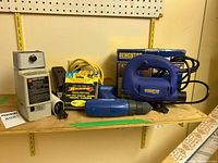Shelf with all items: Black & Decker drill sharpener, staple gun with staples, Mastercraft drill, and Benchtop jigsaw with box