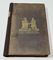 Front cover showing gilt-stamped illustration of two men shaking hands and title ‘CATLIN'S NOTES IN EUROPE’ on dark cloth boards with wear at edges