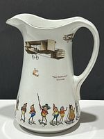 Front side of ceramic pitcher showing colorful illustrations of The Brownies characters walking with a large vintage biplane flying above.