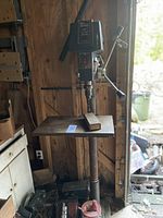 Full view of floor-standing drill press with work table, column and base in workshop