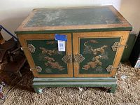 Front view of the closed vintage Chinese style cabinet showing painted floral and cloud motifs with brass hardware.