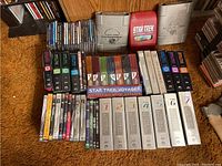 Overall view of the multiple Star Trek DVD box sets arranged on floor showing various series in different packaging styles.