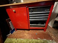 Closed red Craftsman tool cabinet showing drawers and side door under wooden top