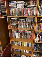 Full view of wooden shelf with multiple shelves filled with DVD cases.