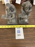 Front view of two chimpanzee figurines seated and reading books, showing size relative to measuring tape.