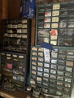 Four hardware organizers stacked with multiple small drawers containing nuts, bolts, screws, washers, with some labels visible