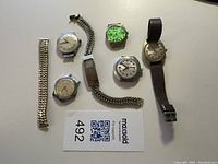 Overhead view showing six watch heads and two loose expansion bands on white table