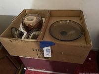 Box containing two sets of clear brown tinted glass Corning Ware pots and lids packed separately with protective styrofoam and paper
