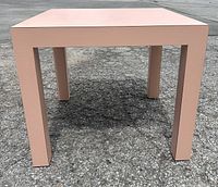 Front angle view of the pink laminate square coffee/side table on asphalt
