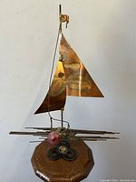 Photo showing front view of Brutalist mixed metal abstract sculpture depicting a man with copper tone and steel elements on wooden base