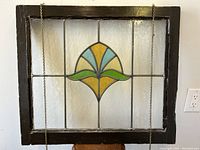 Full front view of panel with dark-finished wood frame and central colored glass motif