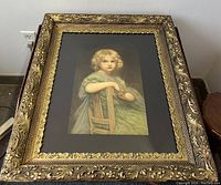 Full front view of gilt frame and black mat showcasing lithograph of girl in green dress