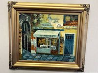 Full view of the gilt framed oil painting depicting a bistro exterior named 'Troubadour' with detailed building facade and signage.