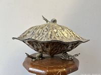 Side angle showing the silver plated serving dish lid shaped like a cabbage leaf with snails on base and lid.