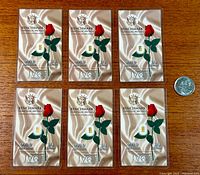 Front view of six unopened 1/4 grain 999.9 fine gold bullion bars with a US quarter coin for size reference, showing Benchmark Strategic Metals branding and certificate of authenticity sealed in plastic.