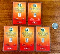 Five Benchmark Strategic Metals 5 grain .999 fine silver bullion bars unopened in tamper evident packaging placed on a wood surface with a quarter coin for size reference.