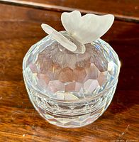 Close-up of round faceted crystal trinket box with frosted butterfly on top