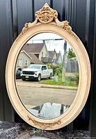 Front view of vintage oval mirror showing carved gesso frame with gilding