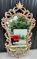 Front view of the large ornate gilded Venetian baroque mirror showing detailed floral and leaf scrollwork on the frame.
