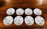 Eight Royal Albert Petit Point bone china bowls arranged on wooden surface showing floral patterns and scalloped edges.