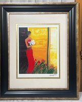Full view of the framed lithograph featuring a woman in a red dress holding white flowers in front of a yellow background with black and red details.