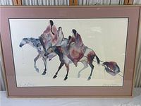 Full view of the framed lithograph showing Native American figures on horses with a mauve matte and wooden frame.