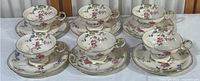 Six Castleton China teacups arranged on matching saucers showing floral pattern and gold trim.