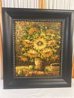 The full front view of the framed painting showing the flowers in the vase on the table with additional elements including fruit and basket on the surface.