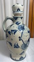 Front side view of the ceramic decanter jug showing floral hand-painted blue patterns and stopper with cork.