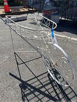 Side view showing the full length of the wrought iron wheelbarrow plant stand, its narrow legs, and decorative front wheel.