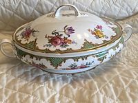 Full view of the round covered vegetable bowl with dual handles and lid, decorated with floral patterns and gold trim.