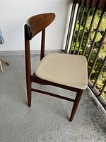 Side view of the Scandia Furniture MCM wood chair showing thick wooden legs, curved backrest, and beige fabric seat cushion.