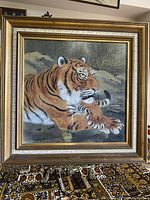 Framed original hand painted artwork of a tiger on silk, shown from a front view on a table with patterned cloth.