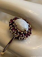 Top-down view showing oval opal center and surrounding red stones.