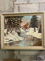Full frontal view of framed winter landscape painting depicting trees, stream, and watermill.