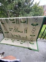Full view of vintage quilt hanging from railing showing most of the water lily appliqué pattern and green border.