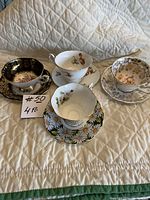 Photo showing all four vintage cup and saucer sets on a quilted white surface.