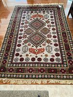 Full view of rectangular machine loomed area rug spread on wood floor showing overall design and colors.