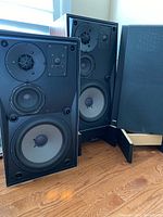 Pair of speakers with one grille removed and one leaning