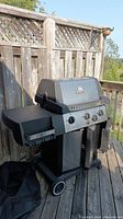 Front and side view of the Broil King three burner natural gas grill on wheeled cart with side shelves.