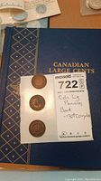 Photo of blue Canadian Large Cents collector's book with three large pennies displayed on paper alongside note indicating incomplete book and three pennies.