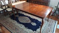 Top-down view of assembled cherry dining table on rug with curved legs visible