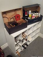 Wide view of white shoe storage shelf with assorted shoe care items and wooden shoe accessories on top and inside compartments