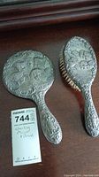 Hairbrush and mirror set showing embossed cherubic angels on silver backs.
