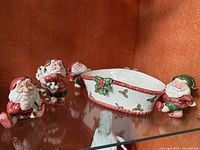 Wide shot of two Christmas elf salt and pepper shakers and serving bowl with elf handles, all ceramic with red, green, white, and gold accents.